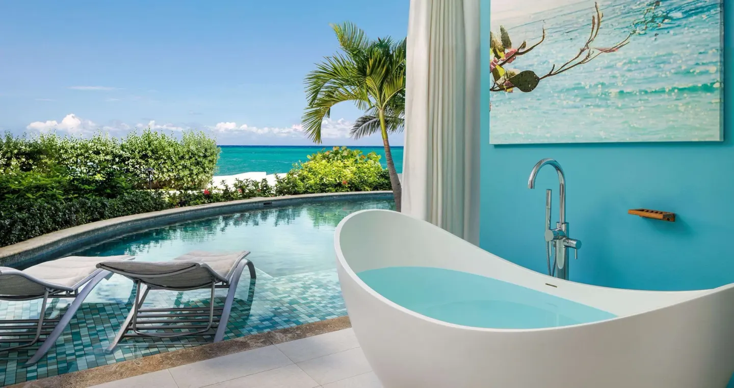 Soaking tub beside a swim-up pool and ocean view in a guest patio at Sandals Montego Bay.