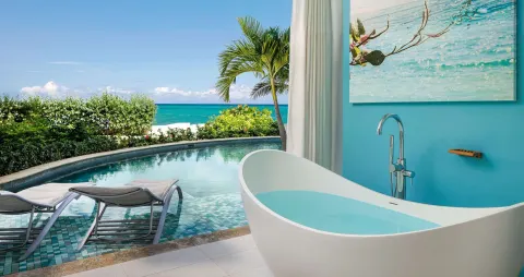 Soaking tub beside a swim-up pool and ocean view in a guest patio at Sandals Montego Bay.