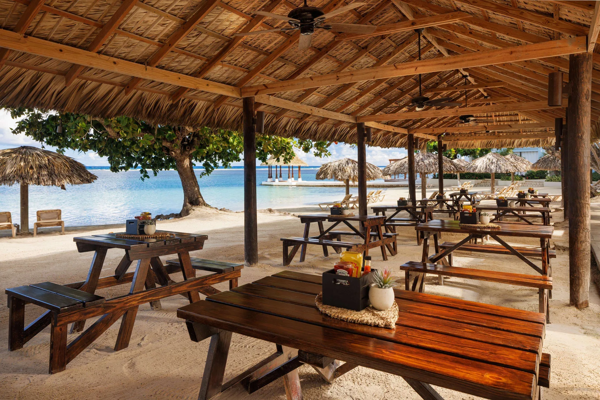 Beachfront open-air picnic tables under a thatched roof at Sandals Montego Bay.