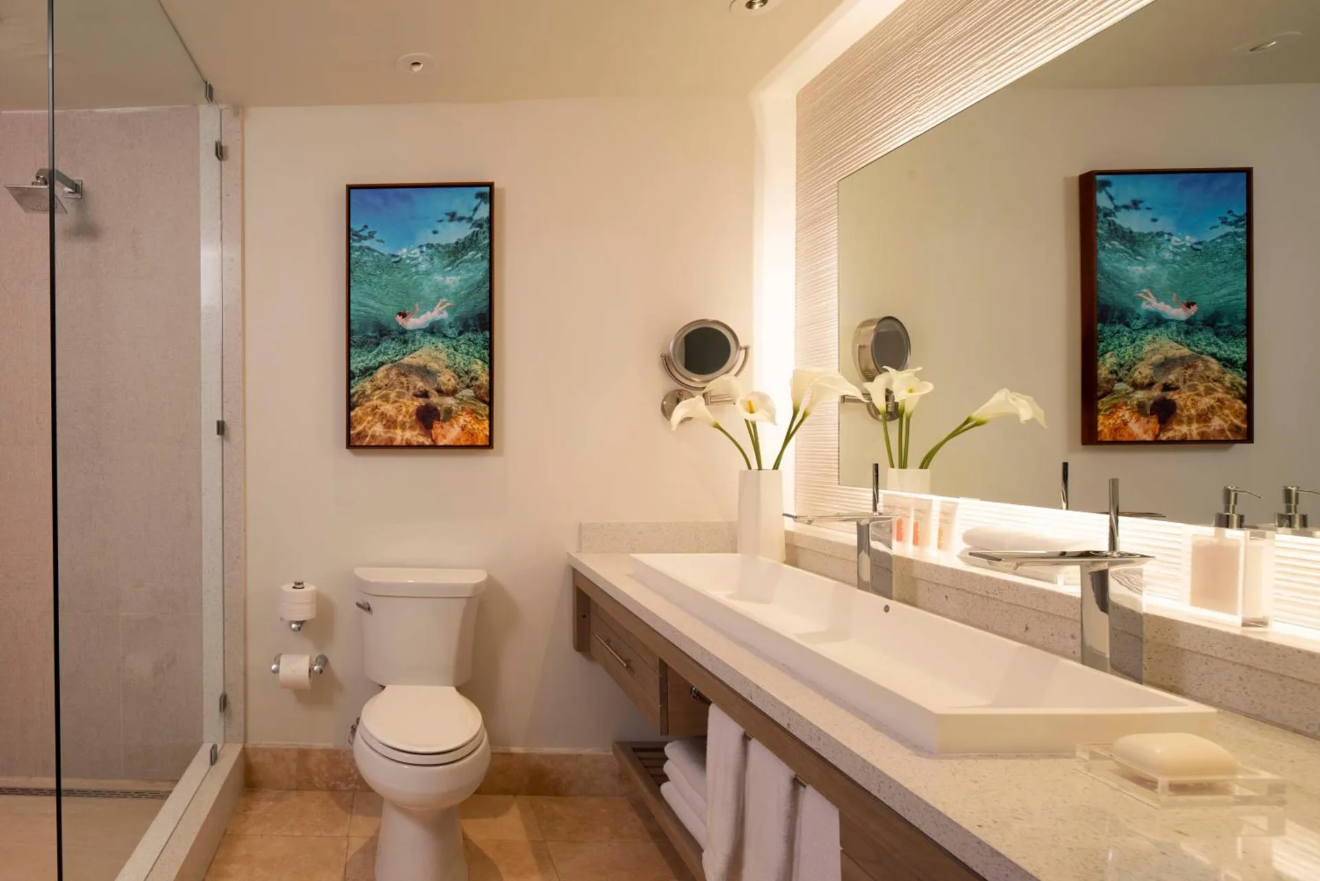Bathroom vanity, glass shower, and toilet in a guest room at Sandals Montego Bay.