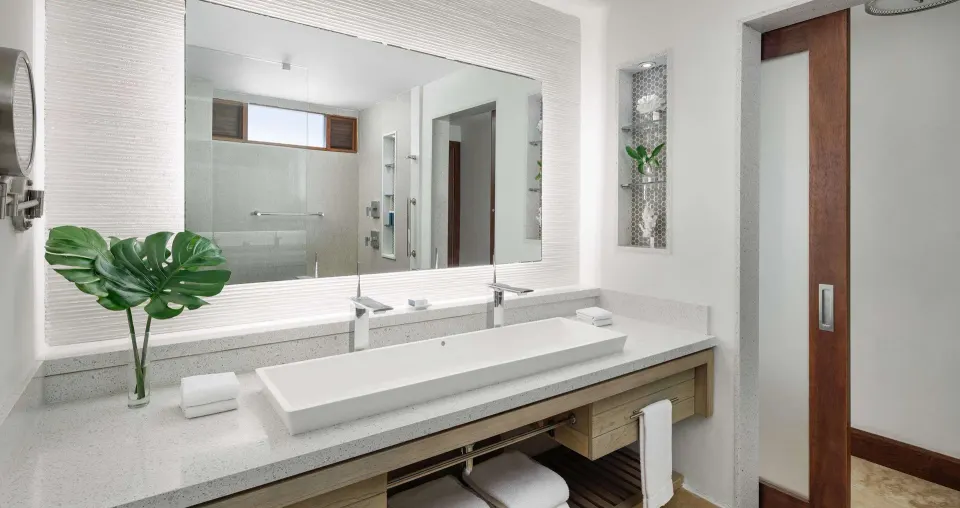 Guest bathroom vanity with long sink and large mirror at Sandals Montego Bay.