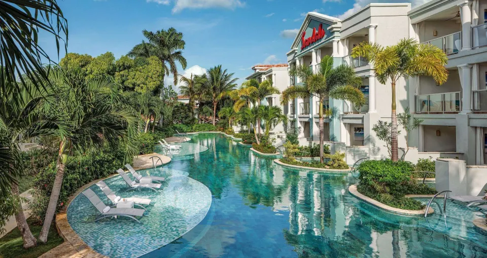 Lagoon pool and guest room balconies framed by palms at Sandals Montego Bay.