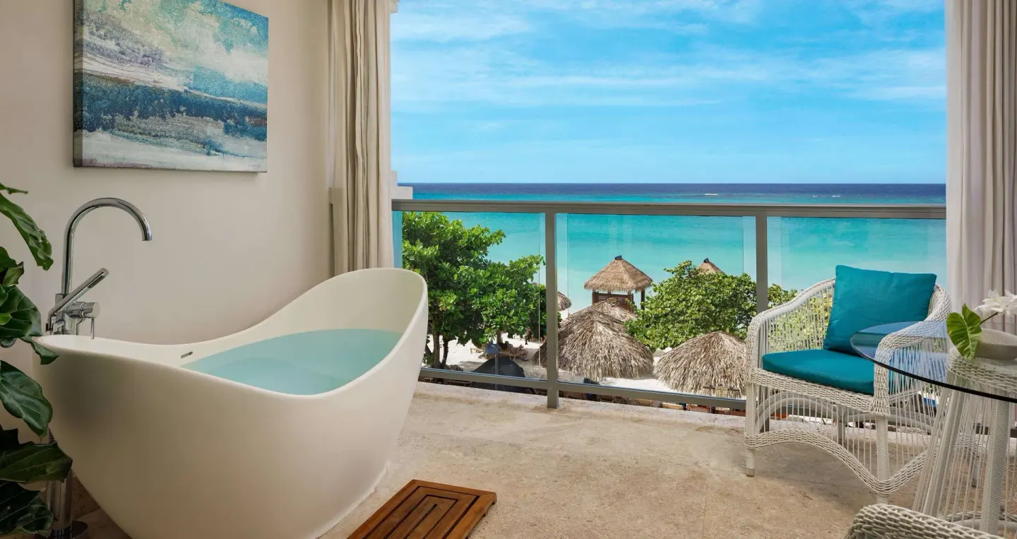 Freestanding tub and balcony seating with ocean view at Sandals Montego Bay.