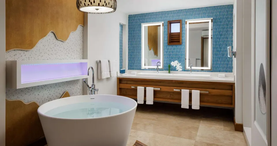 Suite bathroom at Sandals Montego Bay with freestanding tub, double vanity and blue tile wall.