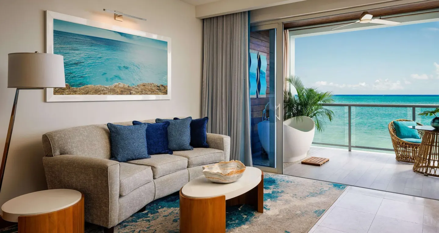 Ocean-view living area in a romantic suite at Sandals Montego Bay with sofa, balcony and turquoise water.
