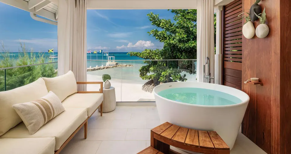 Beachfront balcony soaking tub and cushioned sofa at Sandals Montego Bay.