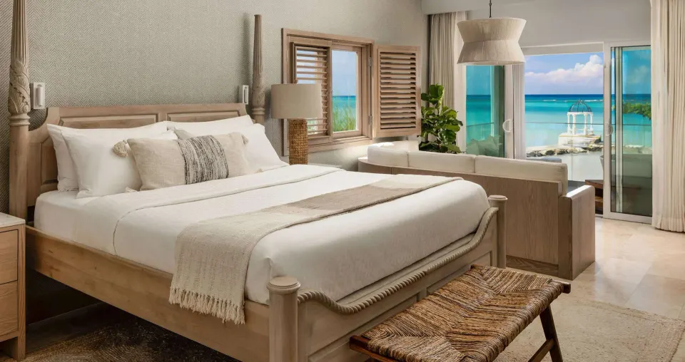 Beachfront king bed suite with ocean-view balcony at Sandals Montego Bay.