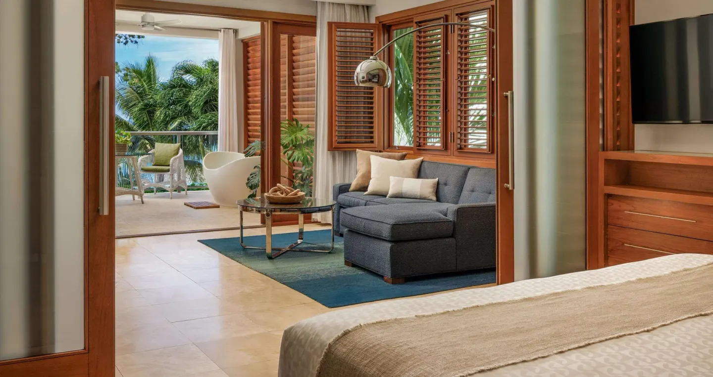 Ocean-view villa bedroom and sitting area with balcony at Sandals Montego Bay.