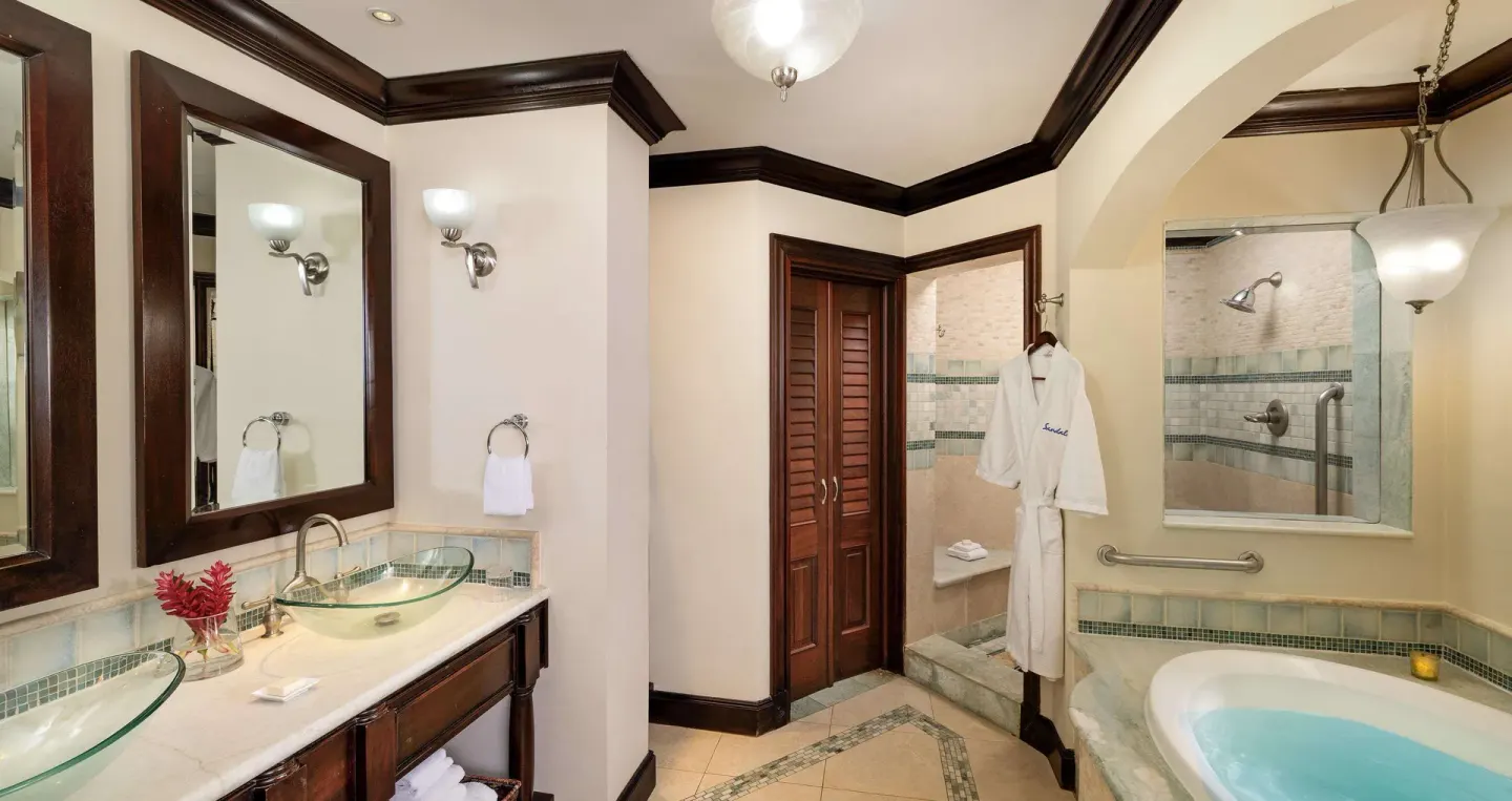 Bathroom with double vanity, soaking tub, and glass shower at Sandals Negril.