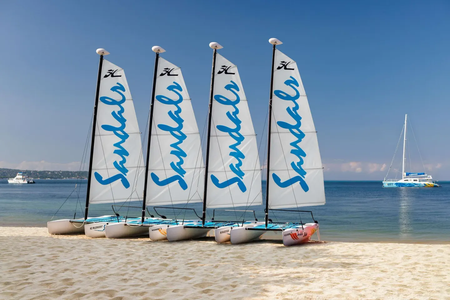 Sailboats lined up on the beach with calm sea behind them at Sandals Negril.