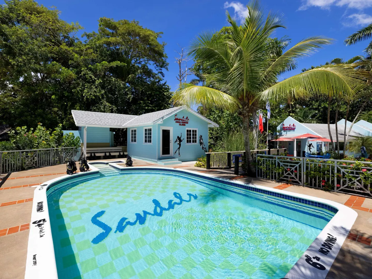 Small dive training pool near a dive center building and palm trees at Sandals Negril.