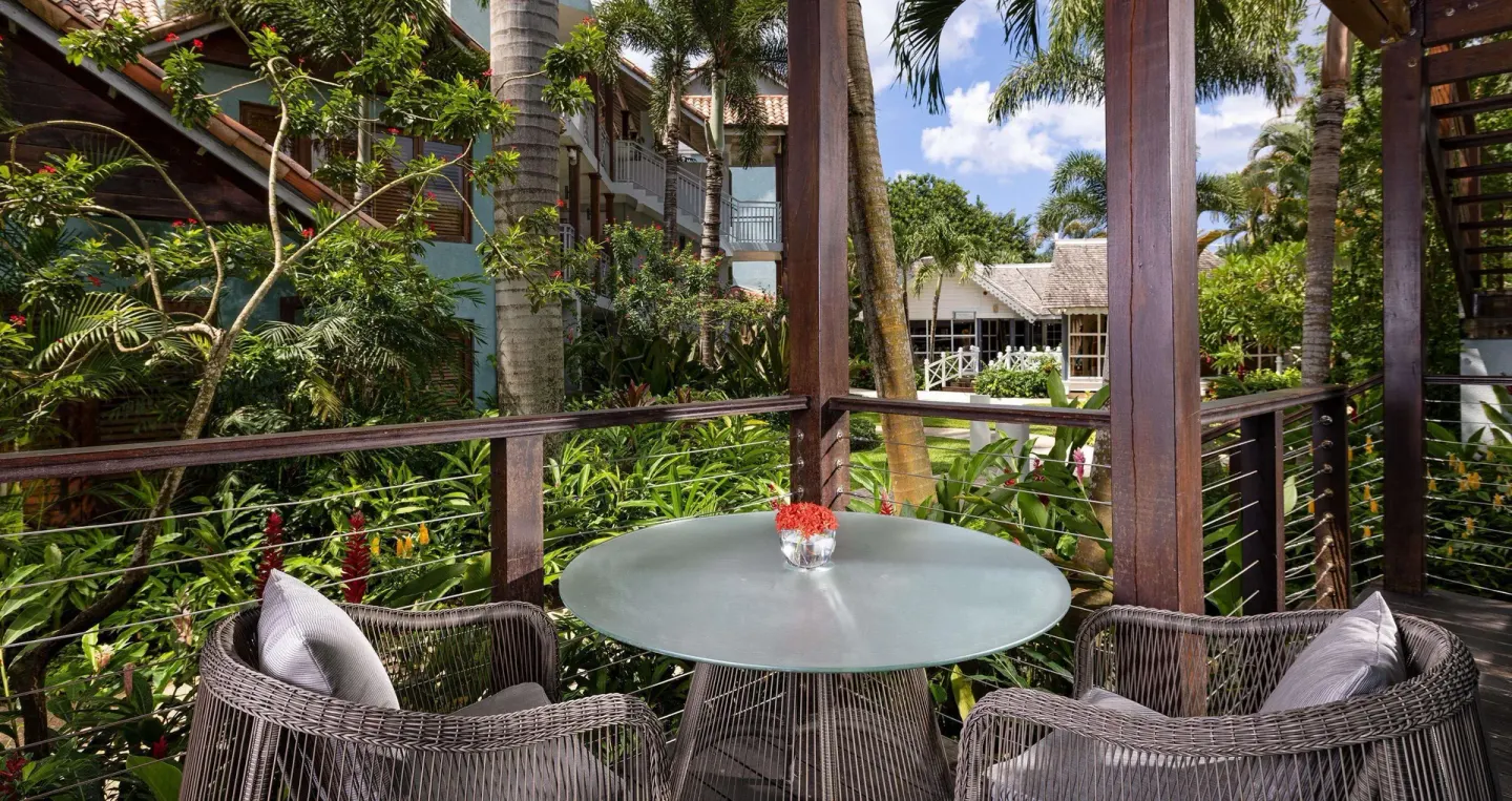Round table and wicker chairs on a garden patio at Sandals Negril.