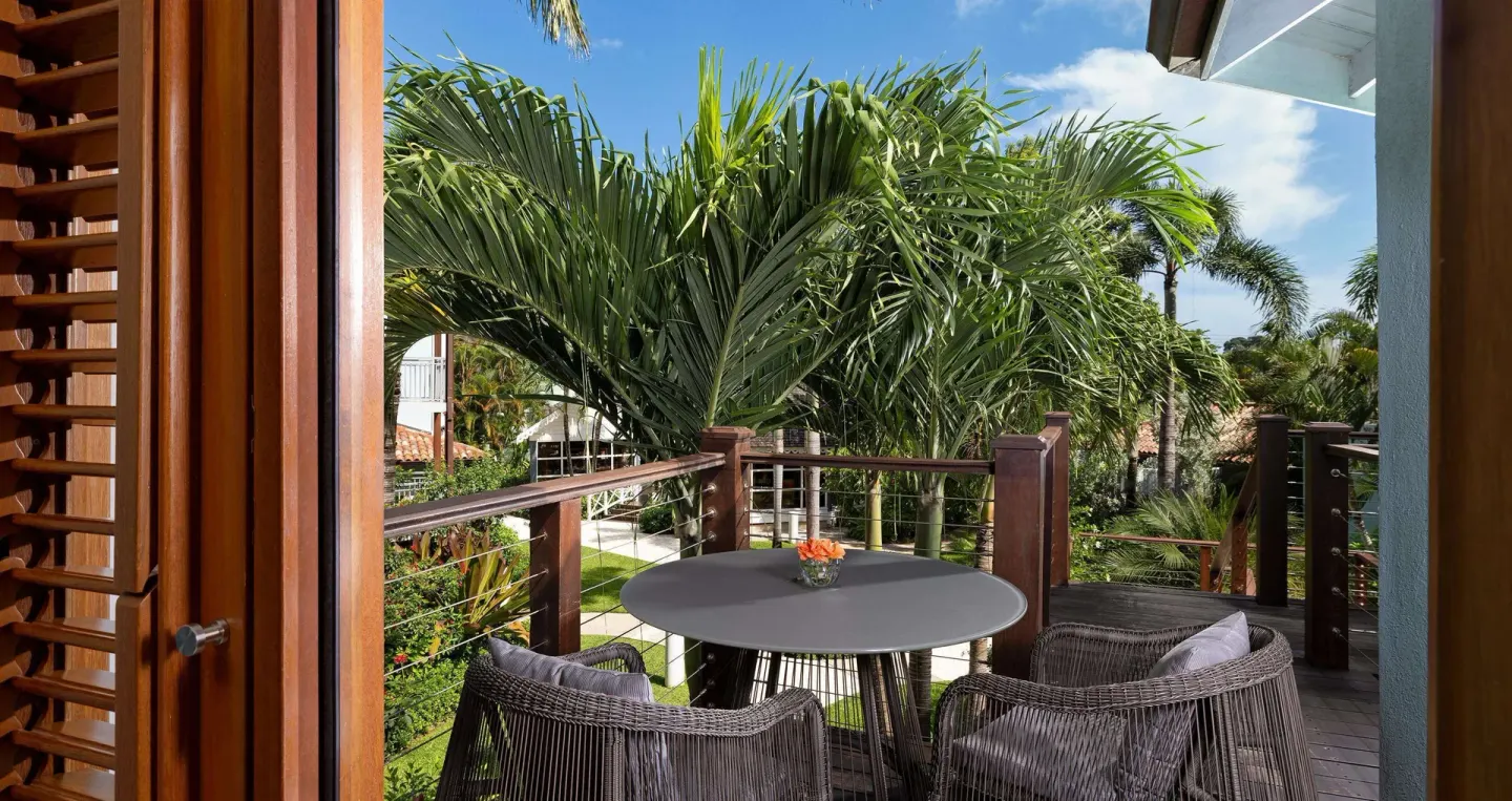 Private balcony with wicker chairs and tropical garden views at Sandals Negril.