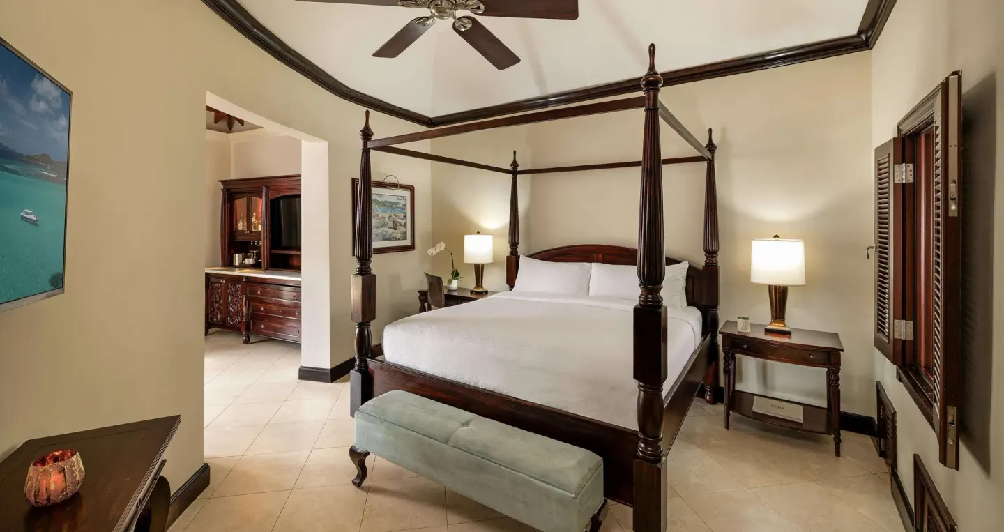 Guest room with a four-poster king bed and dark wood furnishings at Sandals Negril.
