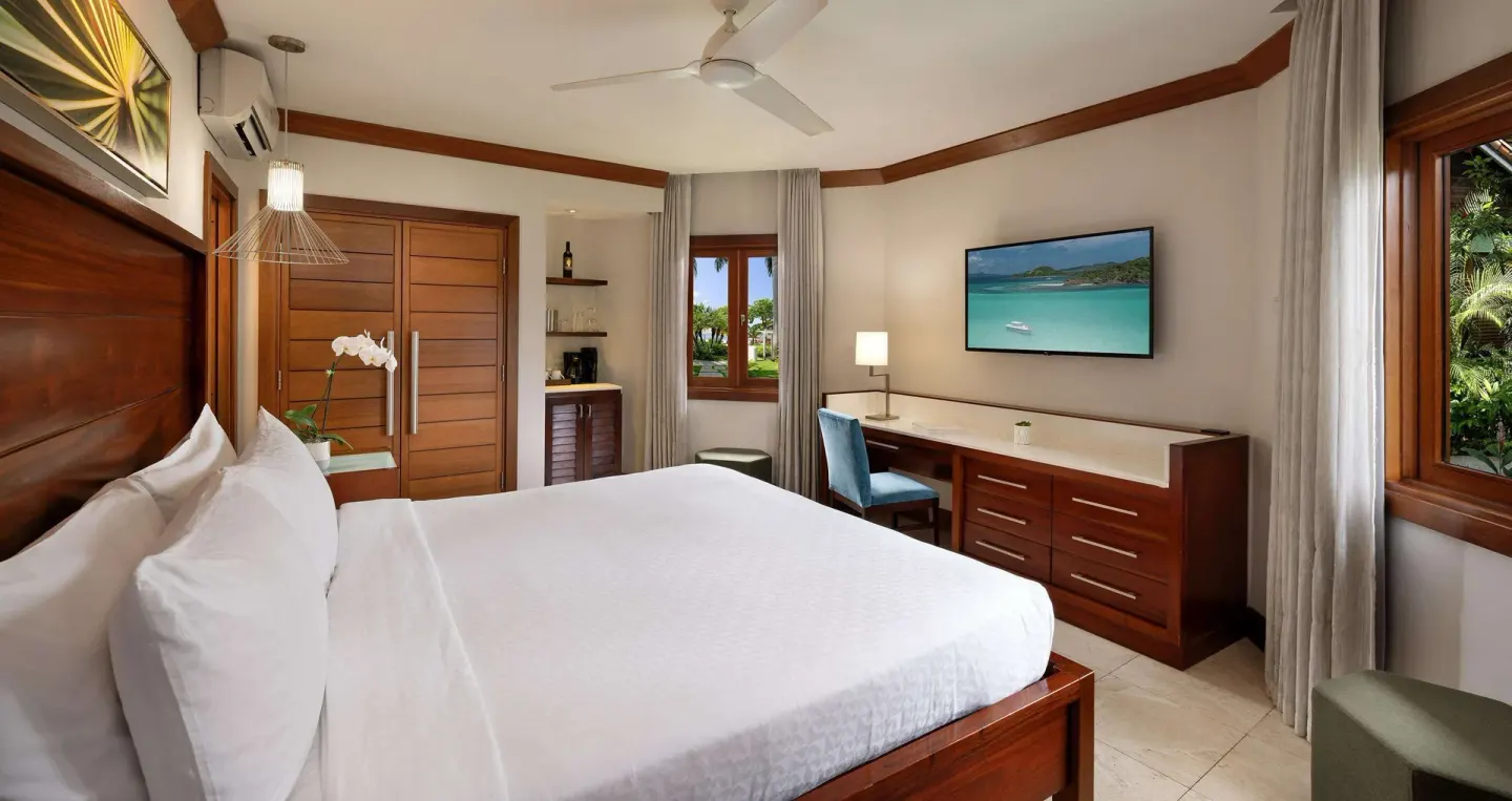 Guest room with a king bed, desk, and wood cabinetry at Sandals Negril.