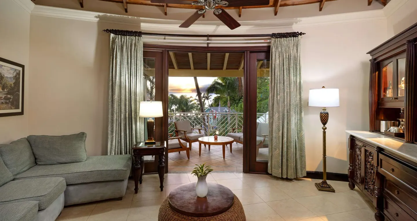 Suite living room with sofa, wet bar, and balcony seating at Sandals Negril.