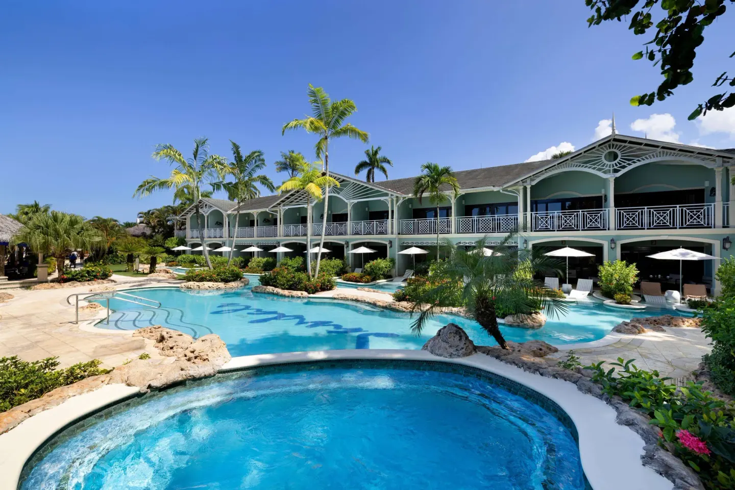 Lagoon-style pool with a round spa area and guest-room balconies at Sandals Negril.