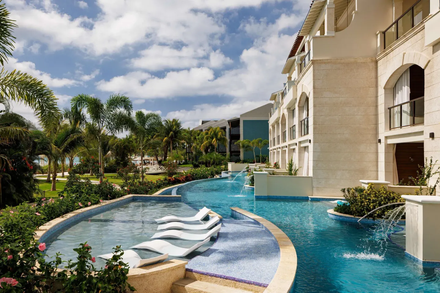 Lagoon-style pool with in-water loungers and arched balconies at Sandals Negril.