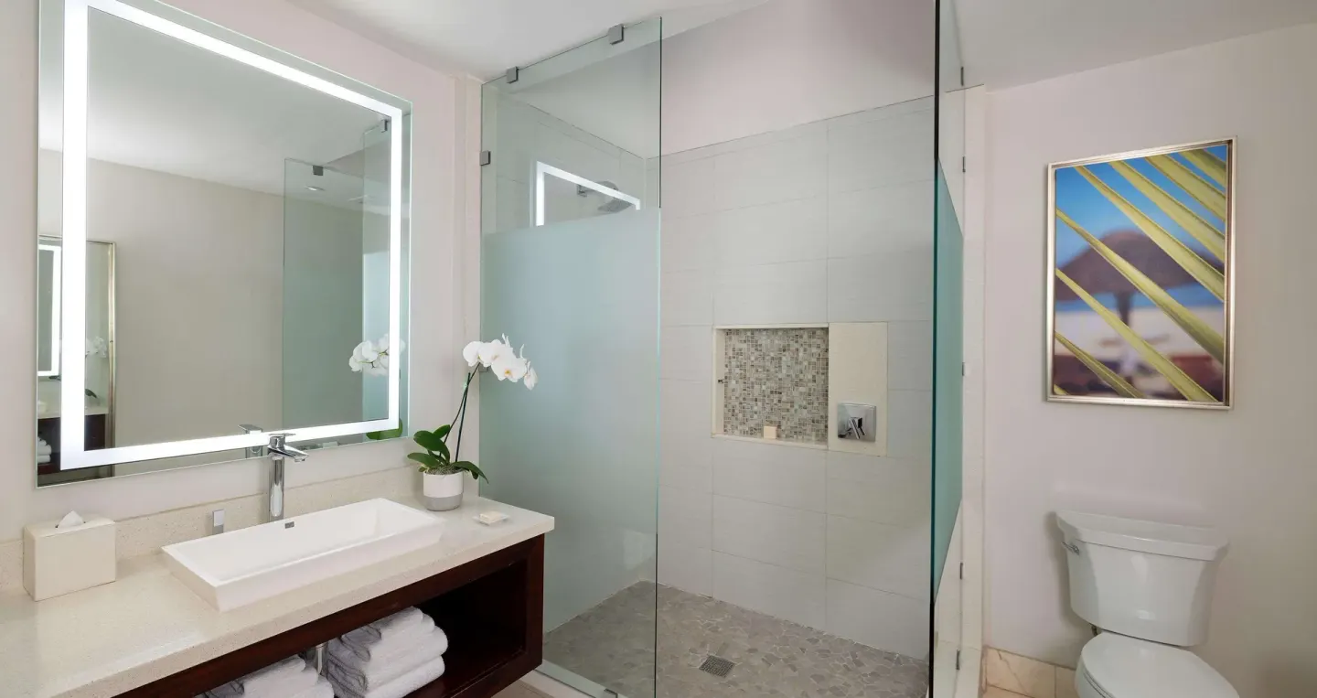 Modern bathroom with lighted mirror and glass shower at Sandals Negril.