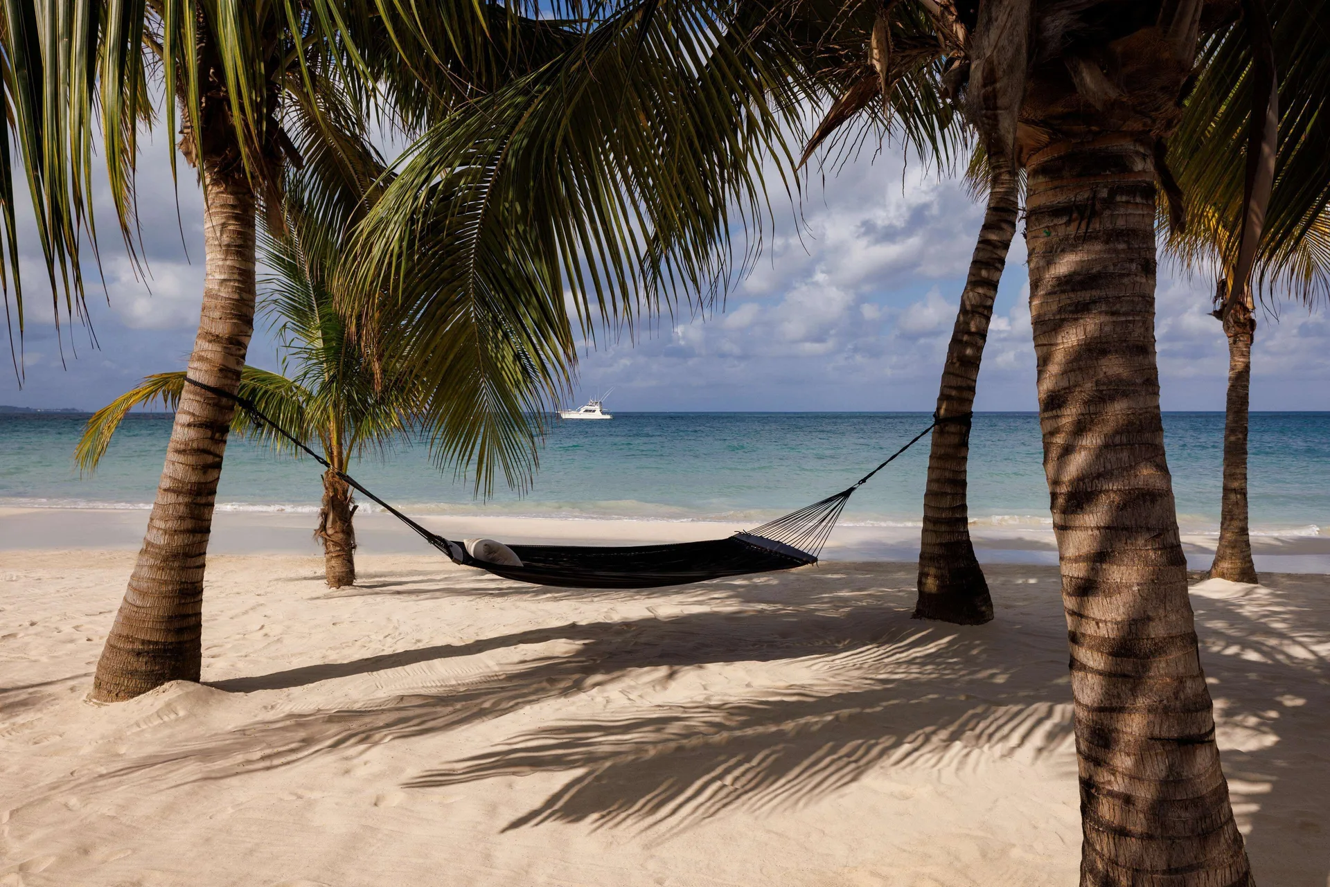 Black hammock strung between palm trees on the beach at Sandals Negril.