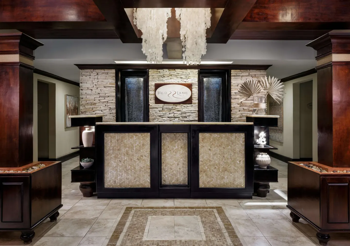 Spa reception desk with stone wall and shell chandelier at Sandals Negril.