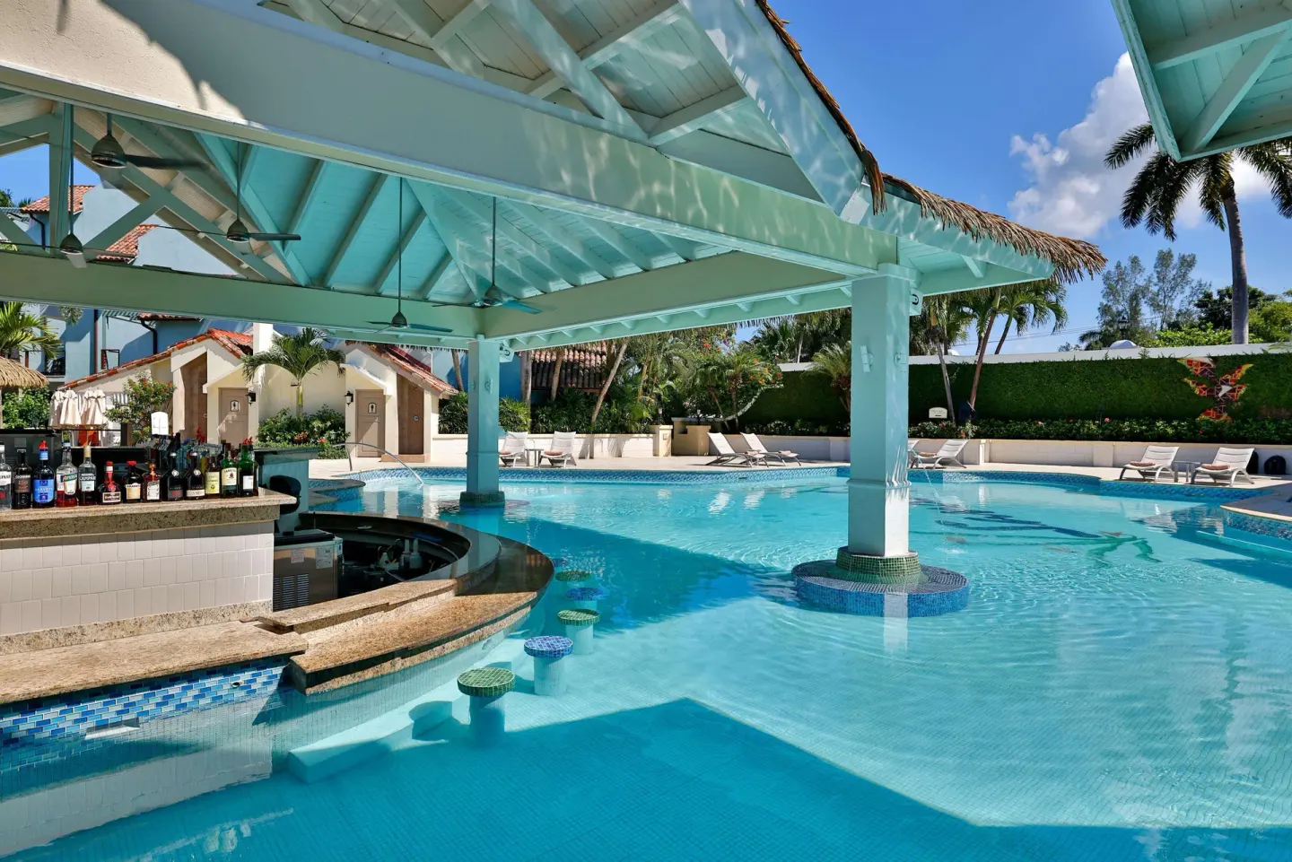 Swim-up pool bar under a pale blue pavilion at Sandals Negril.