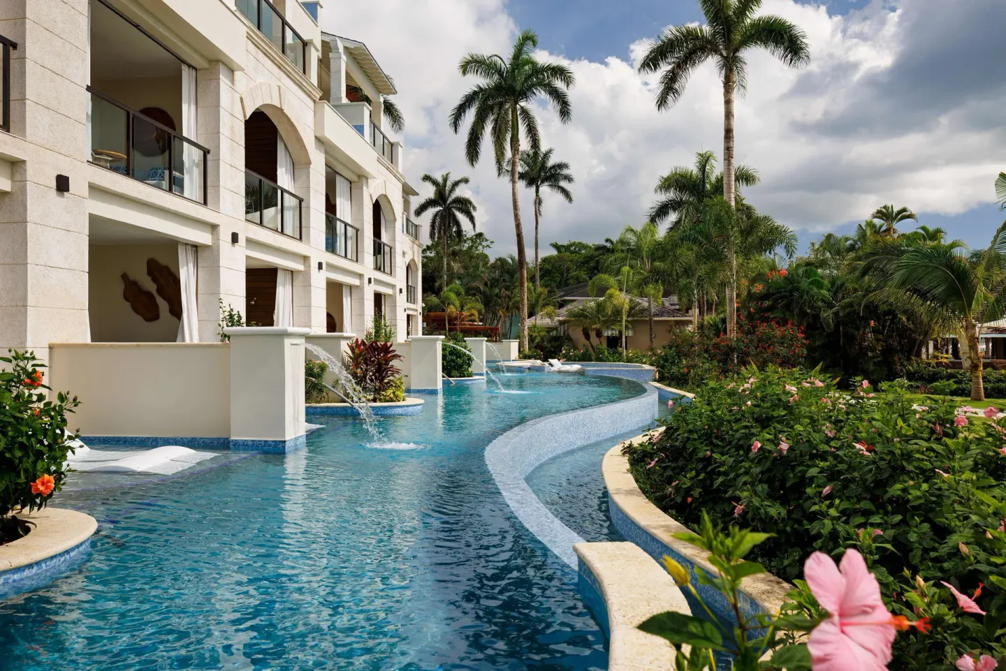 Swim-up pool beside balconies, palms, and flowering gardens at Sandals Negril.