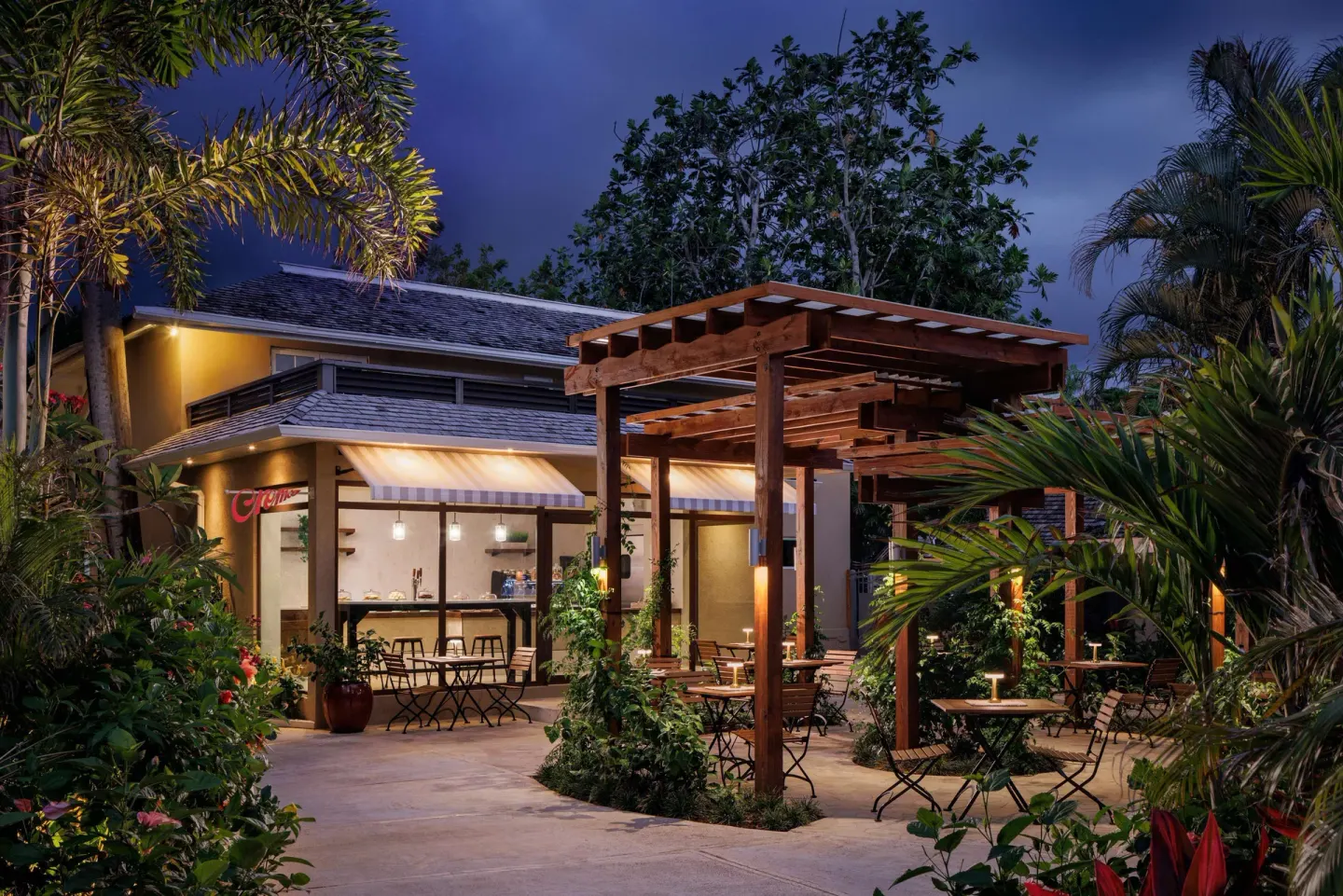 Crema cafe patio with garden seating and pergola at night at Sandals Negril.