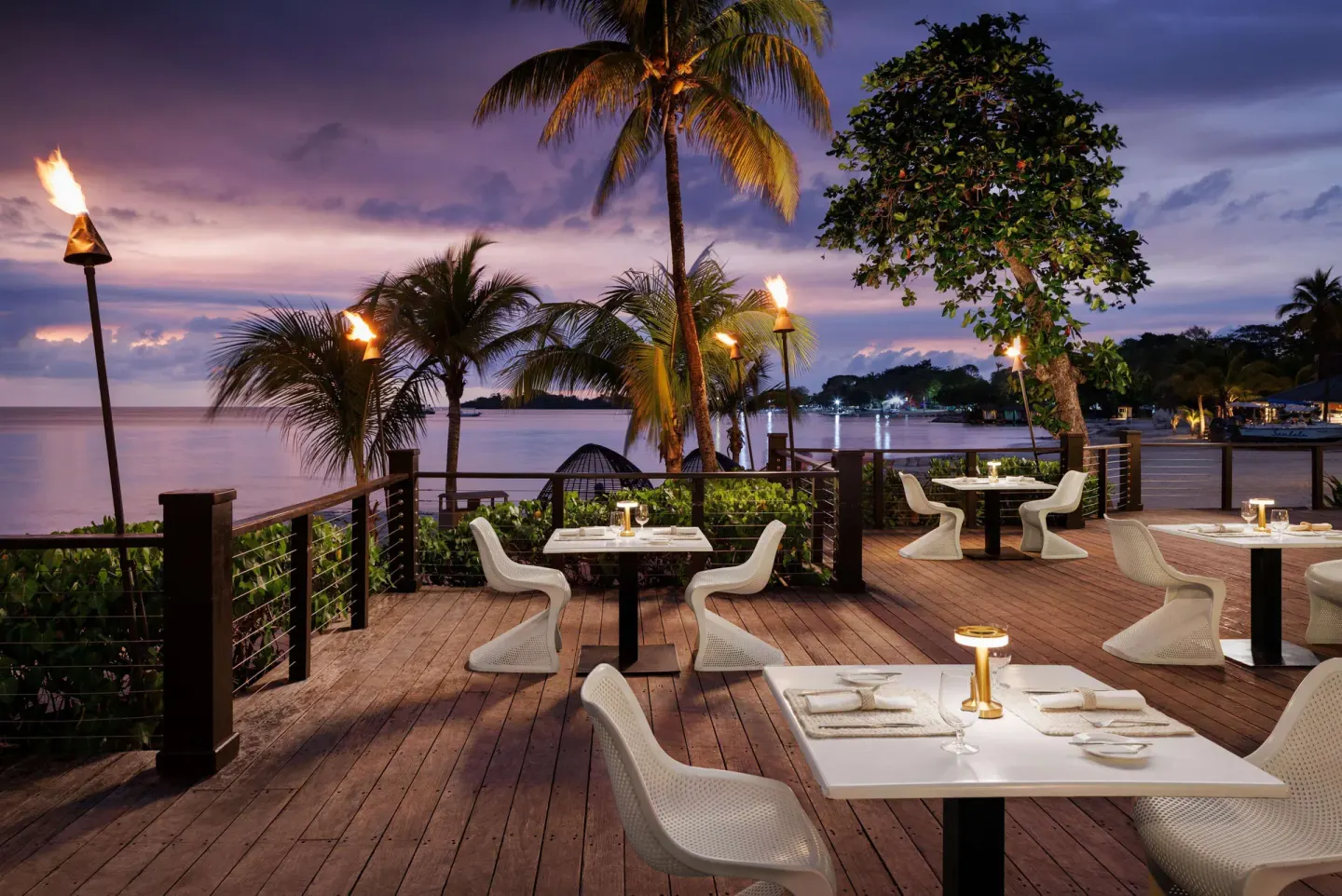 Sunset deck dining with torch lights and ocean views at Sandals Negril.
