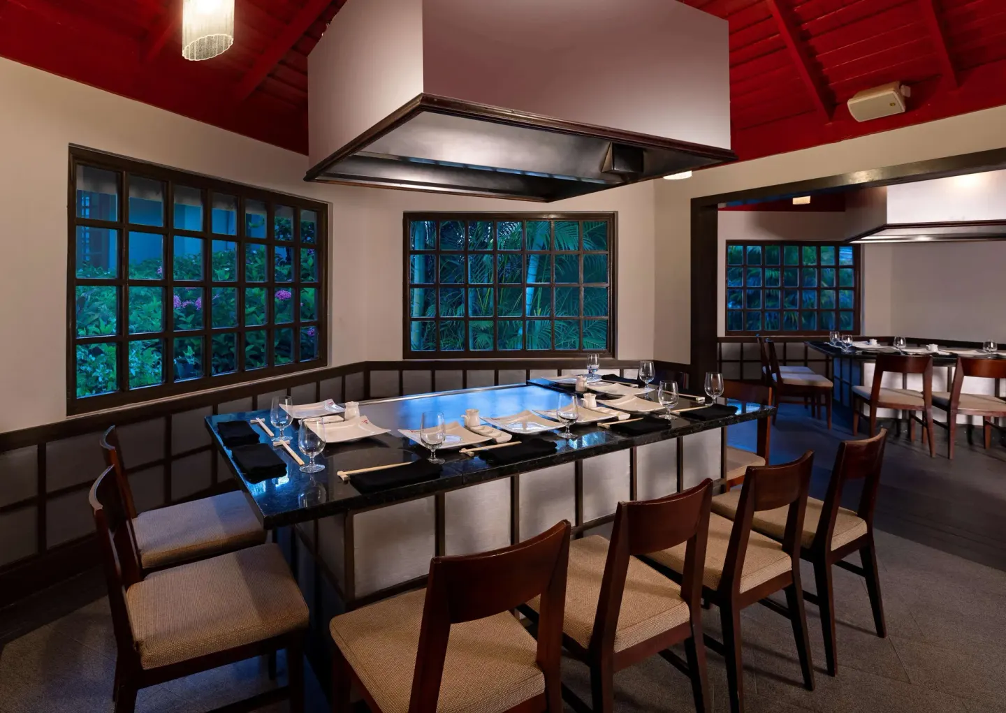 Teppanyaki grill table with place settings in a red-ceiling dining room at Sandals Negril.