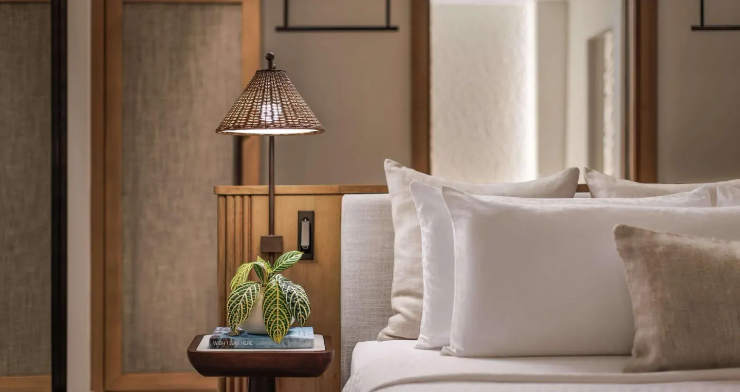 Bedside table and pillows in a Bamboo Grove Skypool suite bedroom at Sandals Negril.