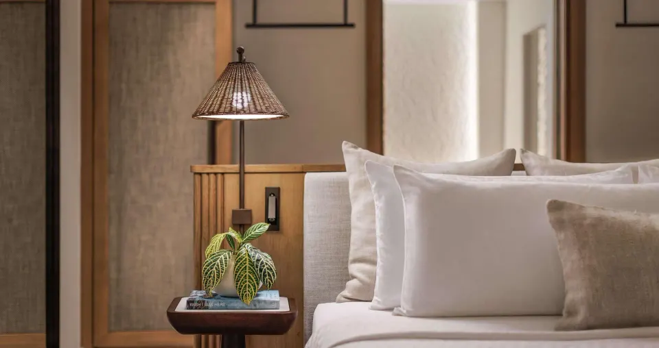 Bedside table and pillows in a Bamboo Grove Skypool suite bedroom at Sandals Negril.