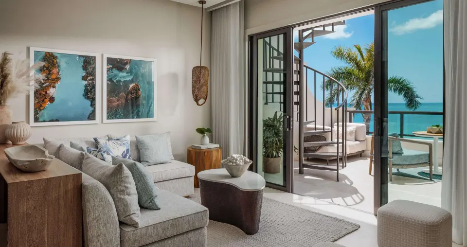 Suite lounge opening to a balcony with spiral stairs and ocean view at Sandals Negril.