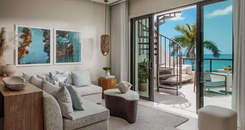 Living room opening to an oceanfront terrace in a Bamboo Grove suite at Sandals Negril.