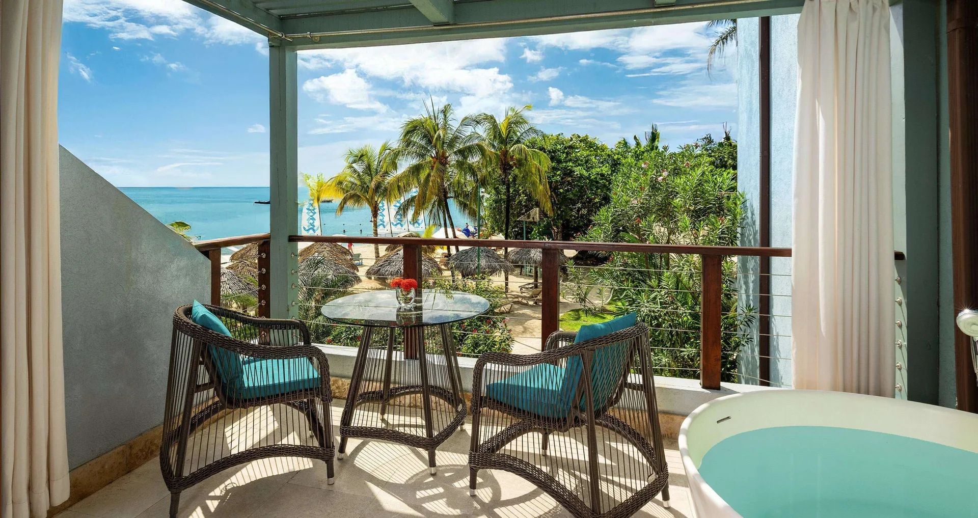 Upper balcony of a villa suite at Sandals Negril with ocean view, seating and soaking tub.