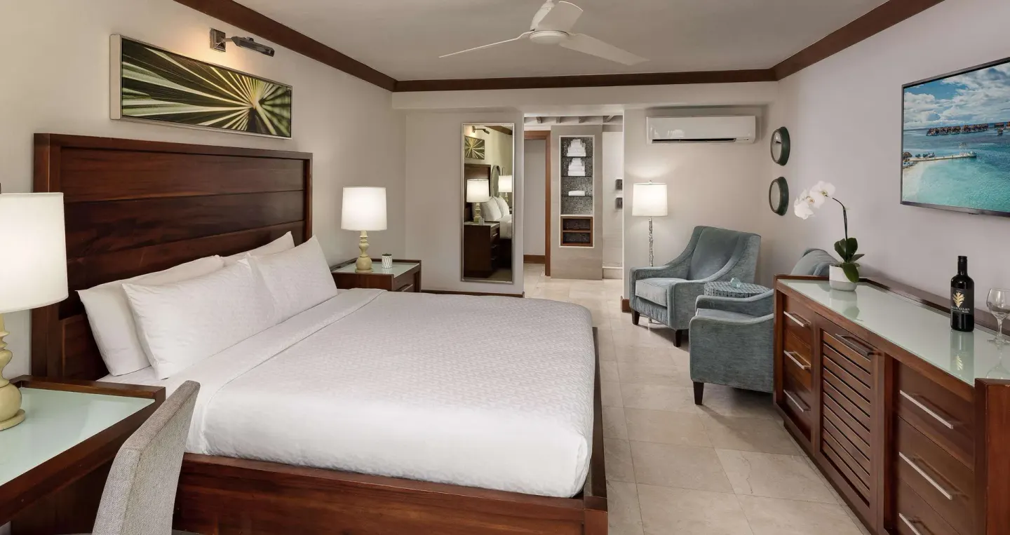Longshore Luxury Room with king bed, seating area, and dresser at Sandals Negril.