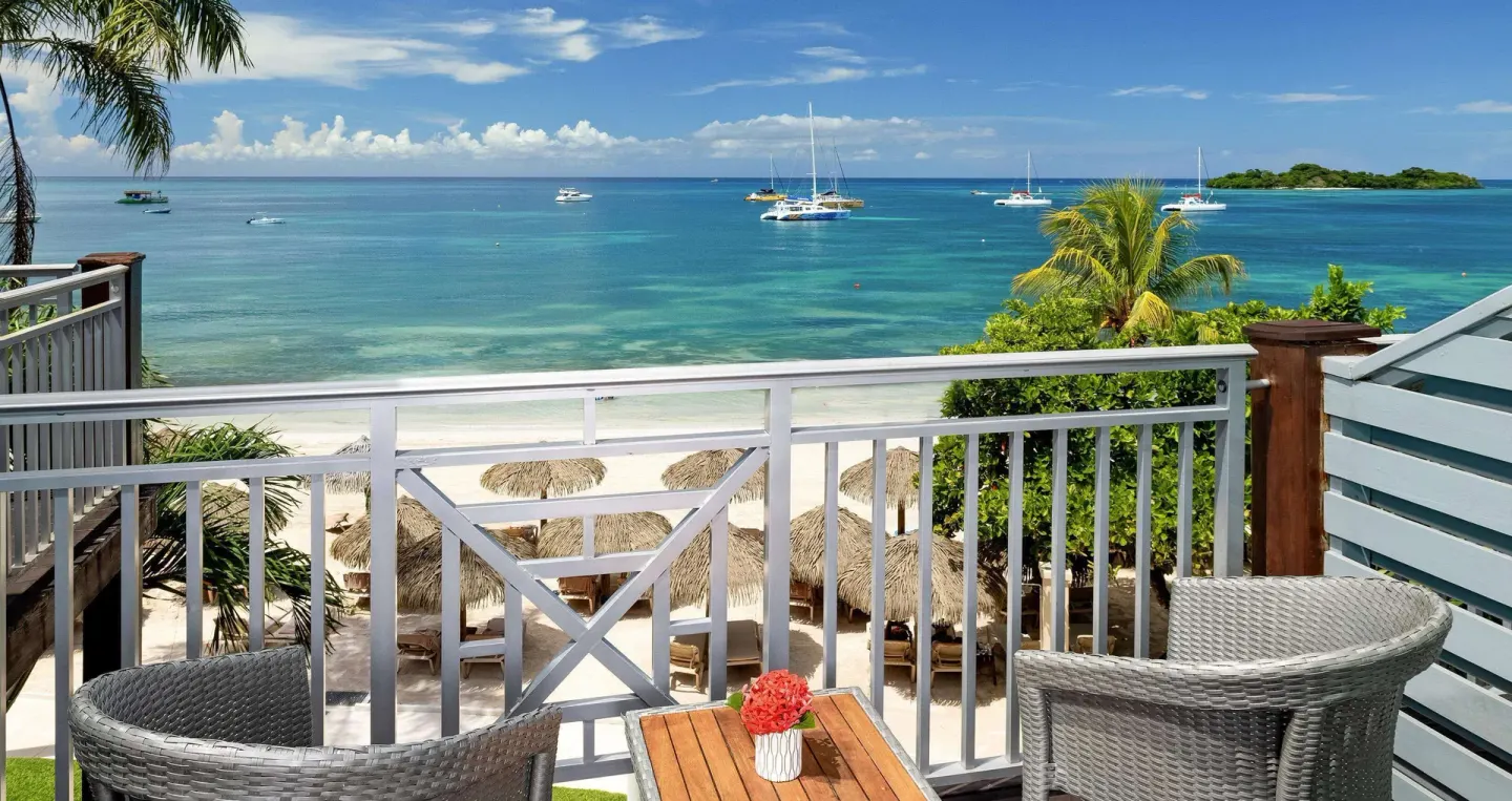 Beachfront balcony with chairs overlooking the sea from a room at Sandals Negril.