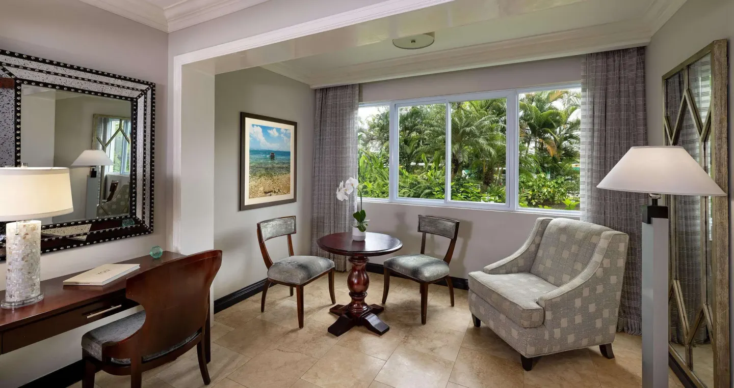 Paradise Deluxe sitting area with desk and garden-facing windows at Sandals Negril.