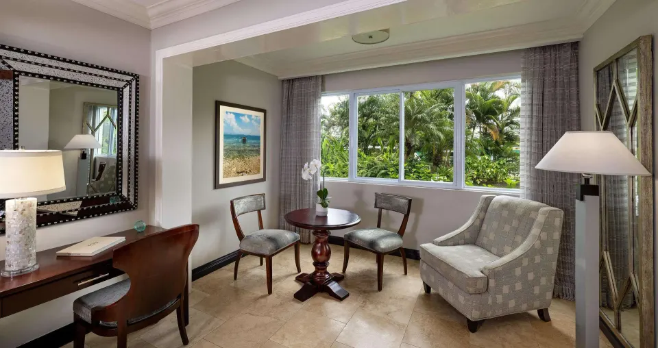 Paradise Deluxe sitting area with desk and garden-facing windows at Sandals Negril.