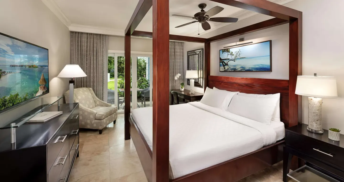 Paradise Premium room with king four-poster bed and seating at Sandals Negril.