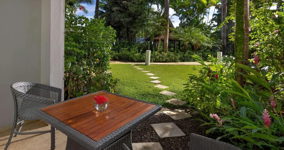 Paradise Premium patio with wicker table and tropical garden at Sandals Negril.