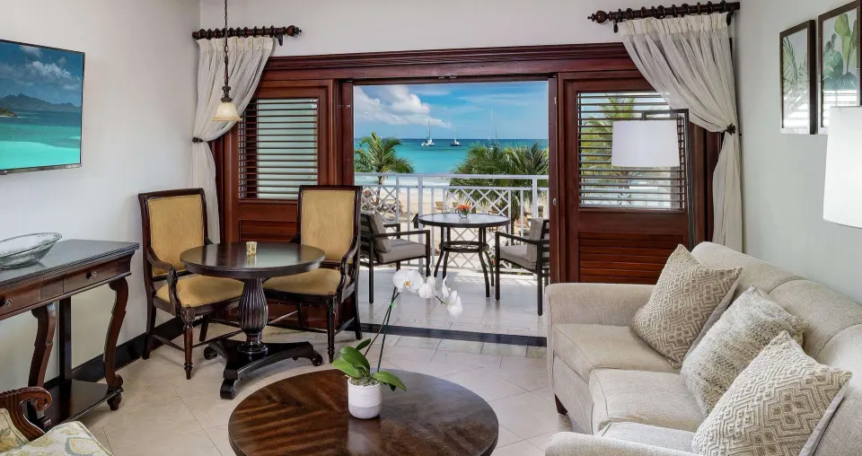 Beachfront living area with balcony and ocean view in a Sundowner suite at Sandals Negril.