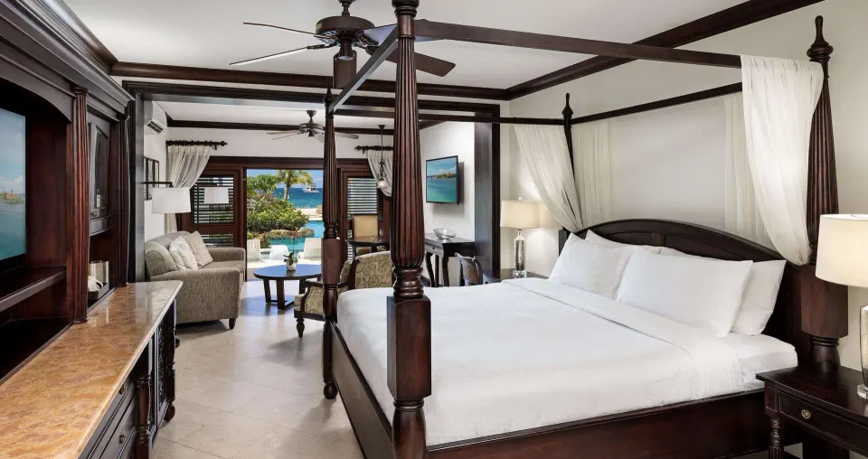Sundowner Swim Up Beachfront One Bedroom Butler Suite king bed and sitting area at Sandals Negril.