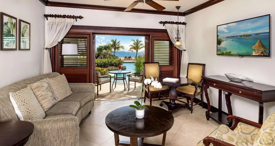 Sundowner Swim Up Beachfront One Bedroom Butler Suite living room at Sandals Negril with patio and sea view.