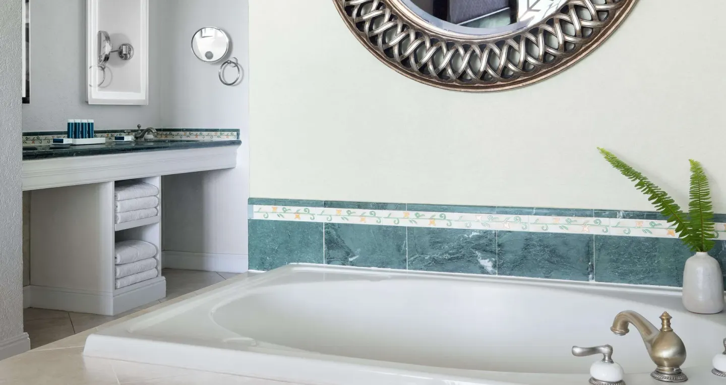 Bathroom soaking tub with vanity, towels, and wall mirror at Sandals Ochi.