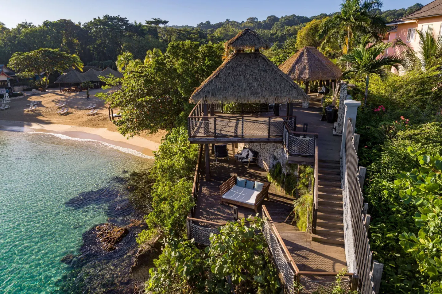 Thatched clifftop deck above clear water and a beach at Sandals Ochi.