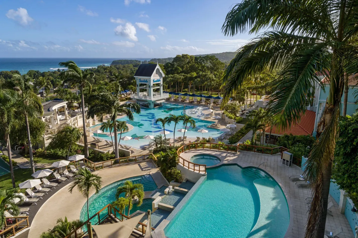 Elevated view of curving pools, palms, and the coastline at Sandals Ochi.