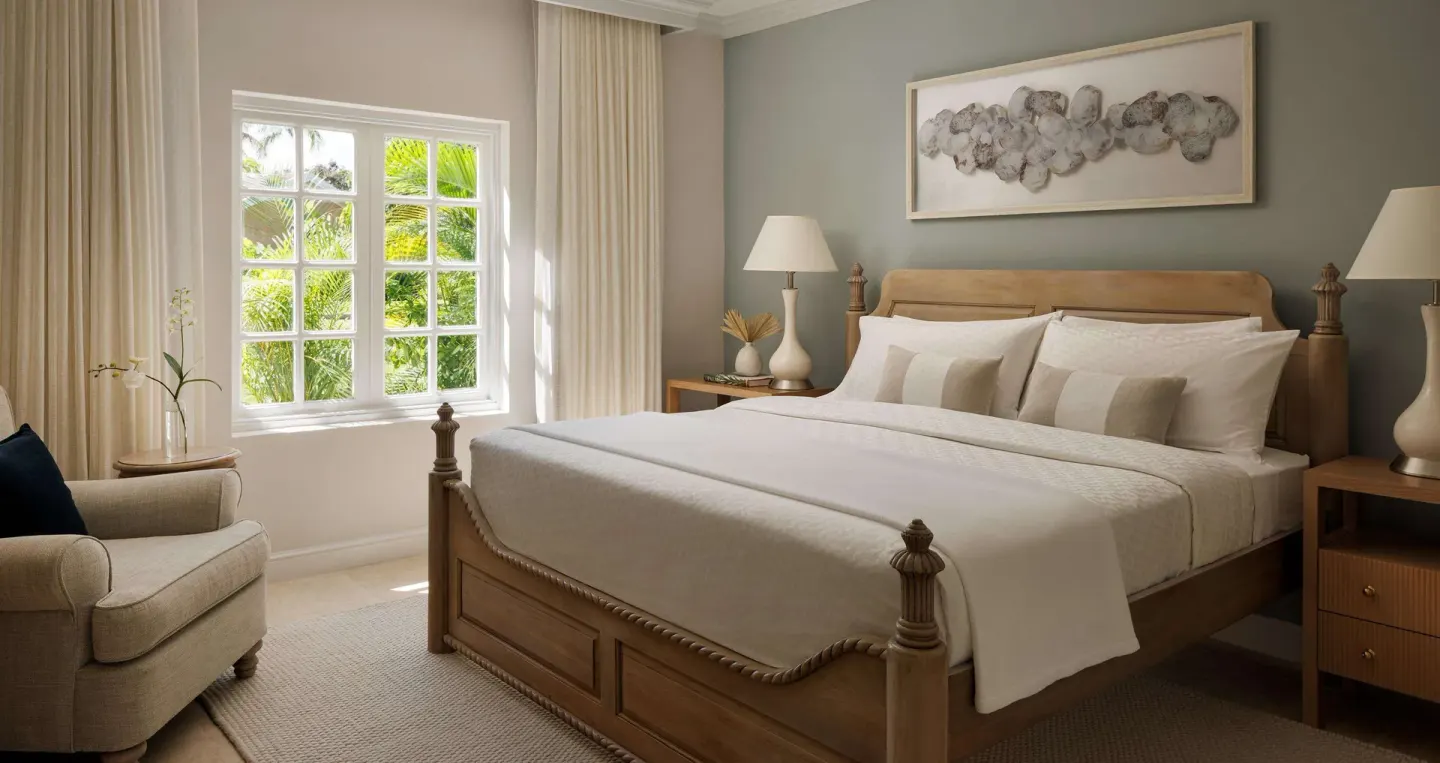 Guest bedroom with a carved king bed and garden-facing window at Sandals Ochi.