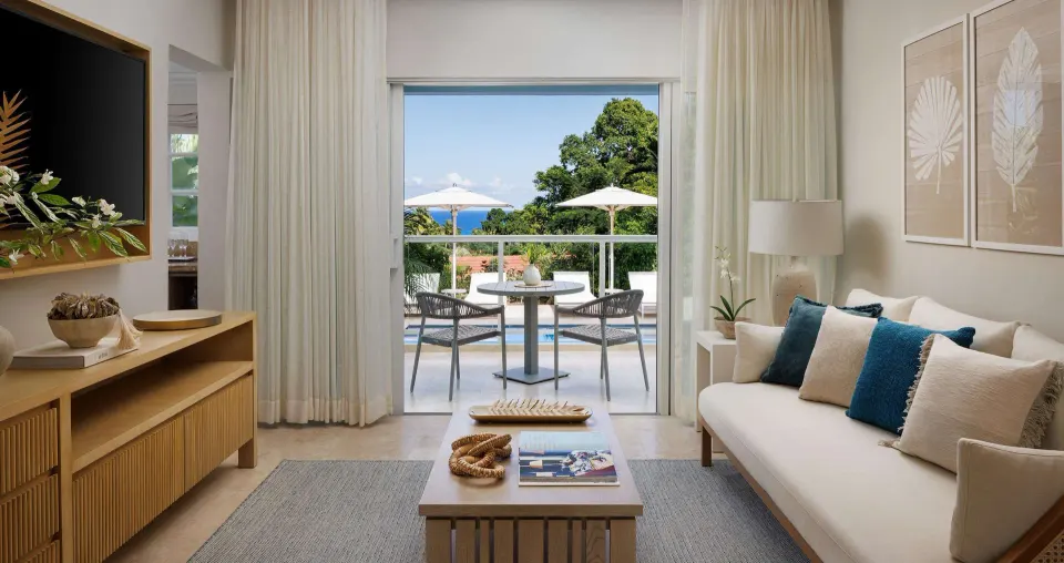 Bright living room with balcony and ocean glimpse at Sandals Ochi.