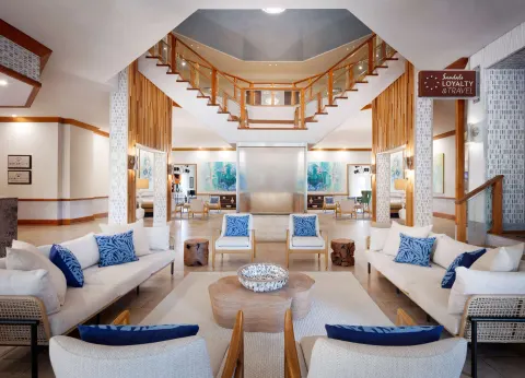 Lobby seating area with staircase, sofas, and blue accent pillows at Sandals Ochi.